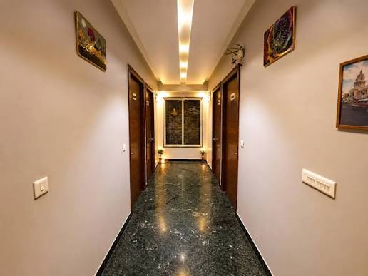 A guest-floor corridor with polished green marble, four dark wood room doors, framed pictures between them and a window at the far end.